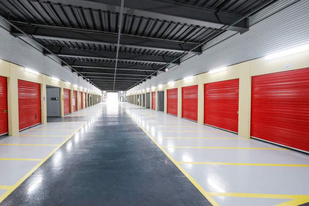 Wide indoor self-storage hallway with red roll-up doors at Your Storage Units Ft Pierce in Fort Pierce, Florida
