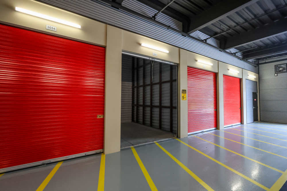 Wide indoor storage corridor with red unit doors and loading lanes at Your Storage Units Vero Beach in Vero Beach, Florida