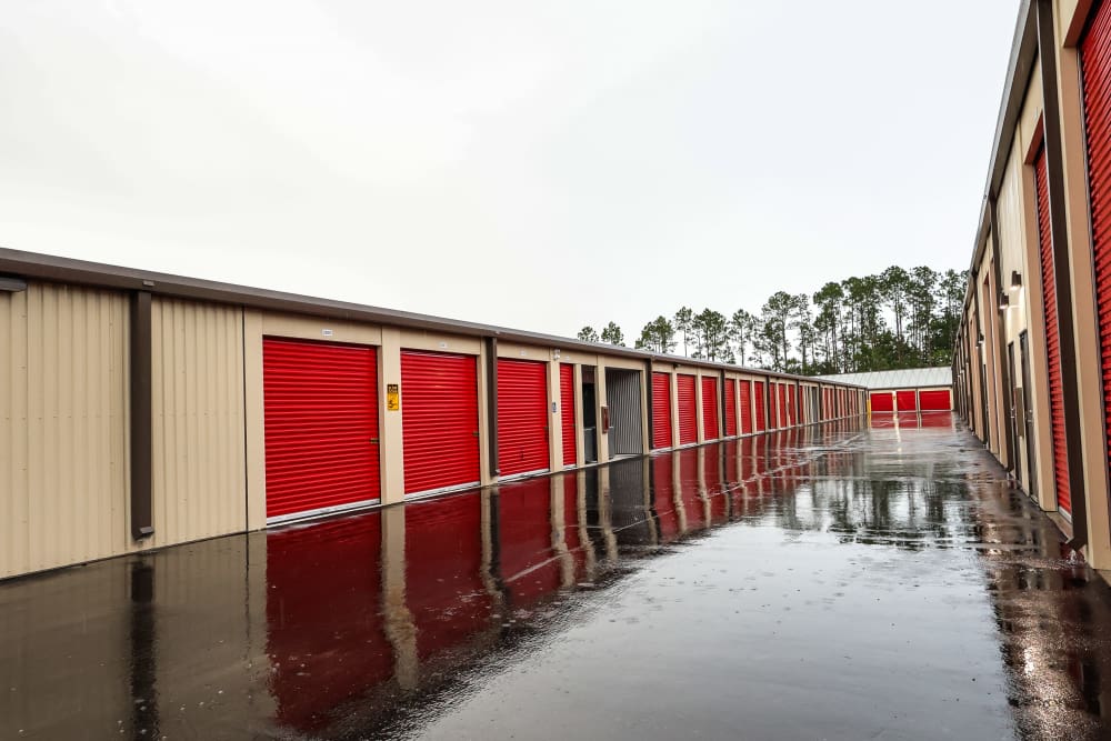 Outdoor storage units with red doors and wide access lane at Your Storage Units Bunnell in Bunnell, Florida