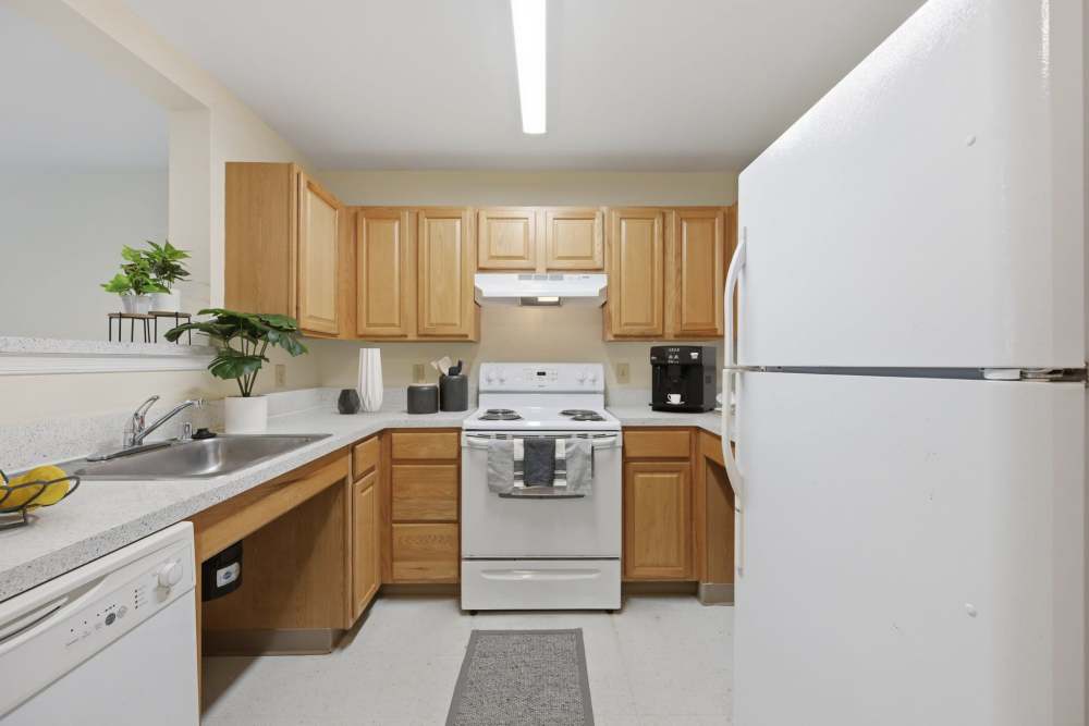 Modern kitchen wth wooden cabinets and white appliances at Waverly Gardens in Woodstock, Maryland