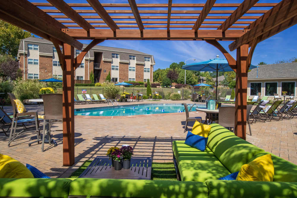 Pool surrounded by lounge chairs and umbrellas at Collins Crossing Apartments in Carrboro, North Carolina