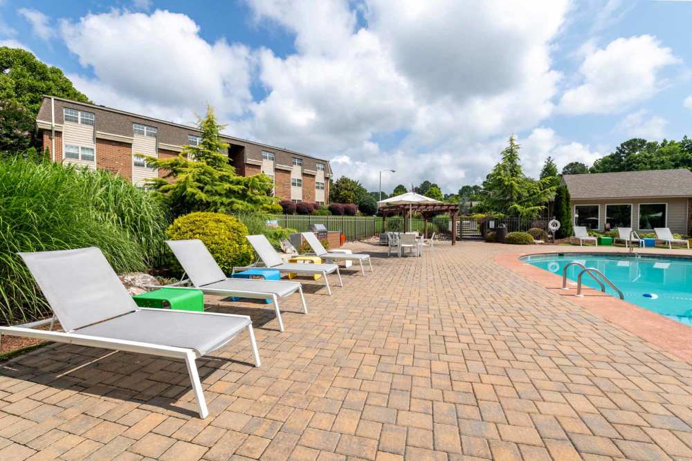 Lounge chairs by a swimming pool at Collins Crossing Apartments in Carrboro, North Carolina