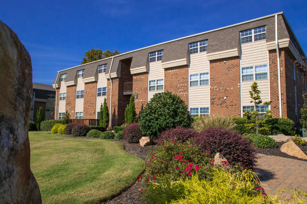 Brick building with large windows and landscaping at Collins Crossing Apartments in Carrboro, North Carolina
