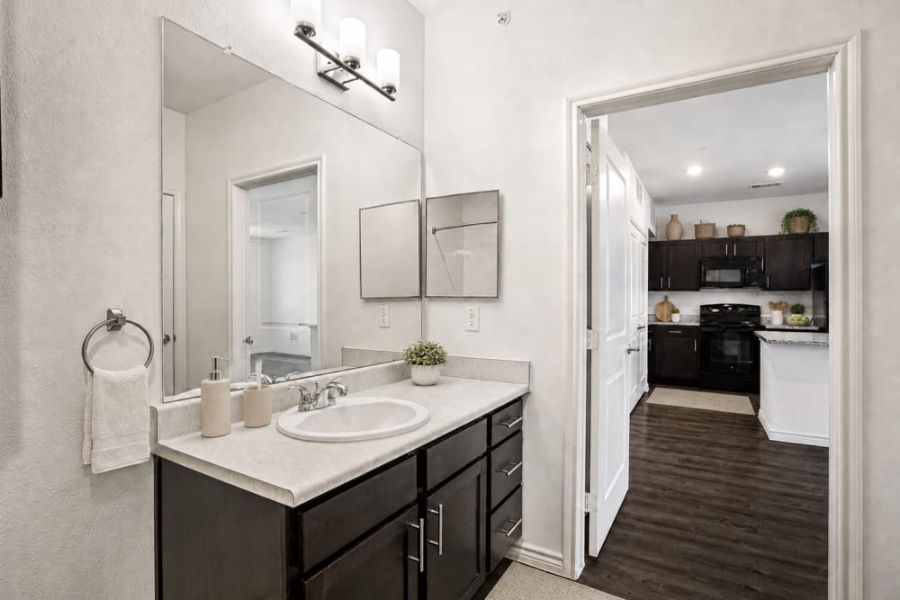 Contemporary bathroom with vanity, large mirror, and modern finishes at Limestone Ridge Apartments in Austin, Texas