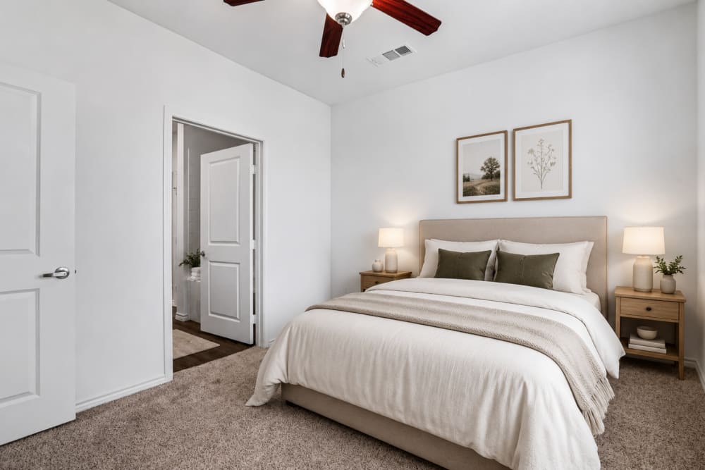 Bright bedroom with large bed, neutral decor, and spacious layout at Limestone Ridge Apartments in Austin, Texas