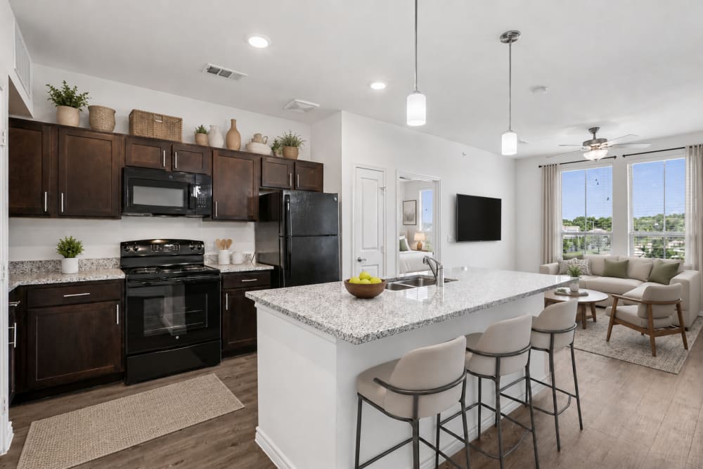 Modern apartment kitchen with white island, bar seating, and stainless steel appliances at Limestone Ridge Apartments in Austin, Texas