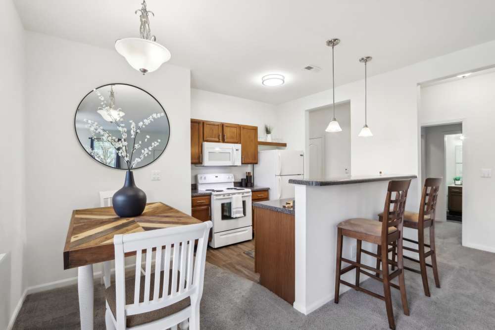Dining area adjacent to kitchen with modern apartment layout at Bluestone in Greenfield, Indiana