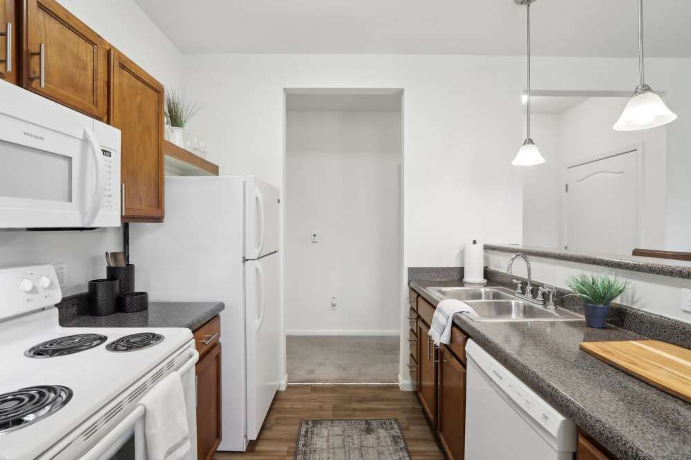 Modern kitchen with wood cabinets and white appliances at Bluestone in Greenfield, Indiana
