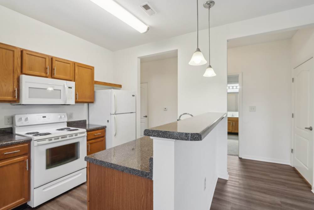 Galley-style kitchen with wood cabinetry and updated finishes at Bluestone in Greenfield, Indiana