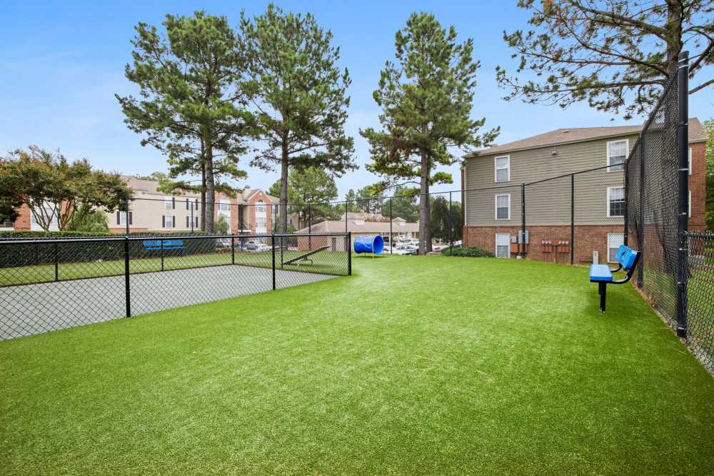 Tennis court with green turf and fence at Stonebridge Crossing Apartment Homes in Cordova, Tennessee