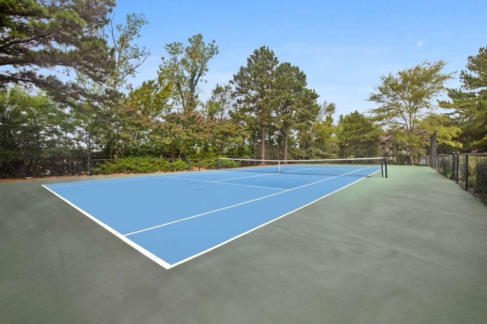 Tennis court with blue surface and net at Stonebridge Crossing Apartment Homes in Cordova, Tennessee