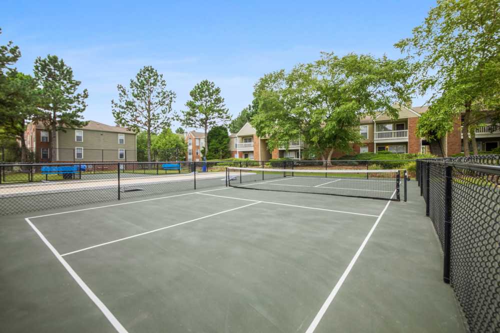 Tennis court with net and surrounding trees at Stonebridge Crossing Apartment Homes in Cordova, Tennessee