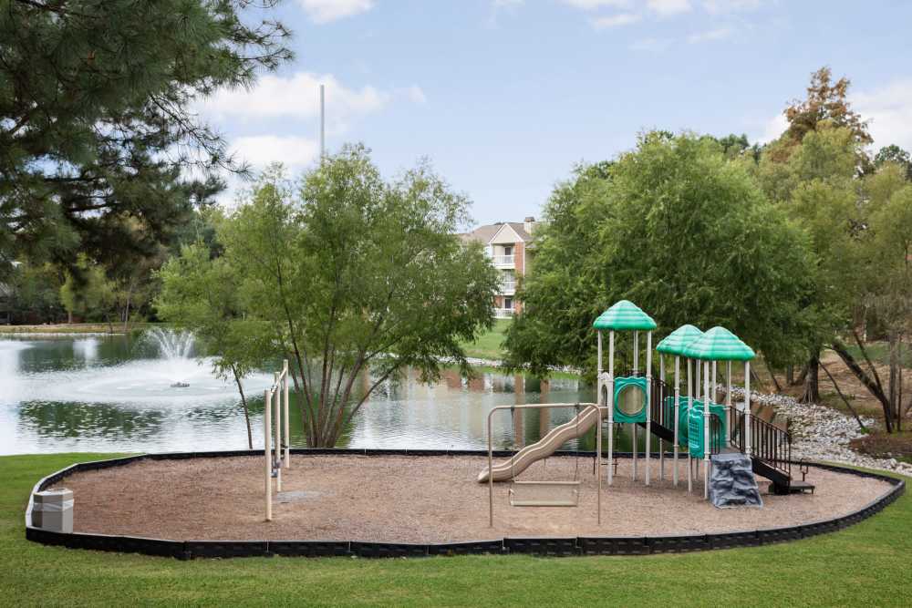 Pond with fountain and playground equipment at Stonebridge Crossing Apartment Homes in Cordova, Tennessee