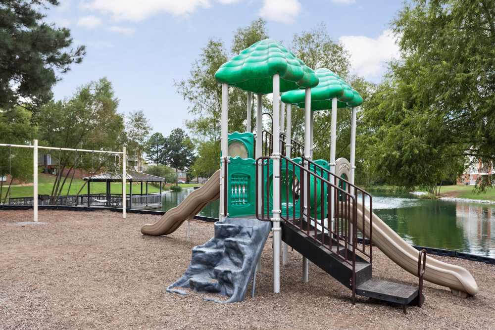 Green playground structure with slides and swings at Stonebridge Crossing Apartment Homes in Cordova, Tennessee