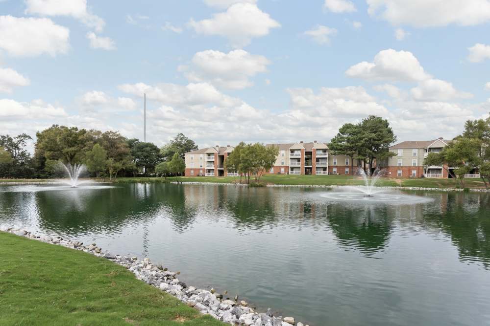 Fountain in a pond with apartment buildings at Stonebridge Crossing Apartment Homes in Cordova, Tennessee
