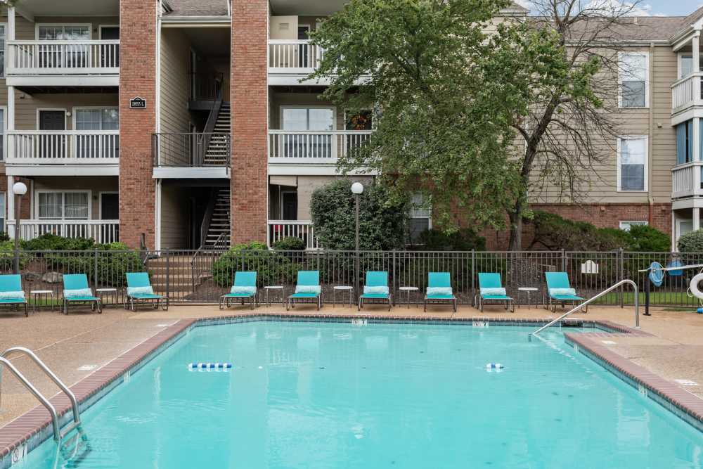 Poolside lounge chairs arranged by the water at Stonebridge Crossing Apartment Homes in Cordova, Tennessee