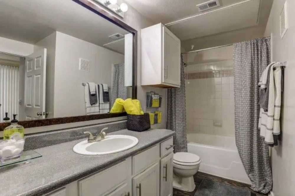 Modern bathroom with granite countertop, large mirror, shower tub combo, and stylish towels at Reeves and Wells in Dallas, Texas