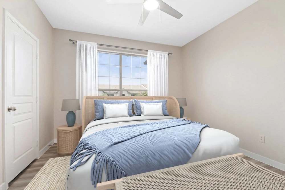 Bright bedroom with wood-style flooring, large window, and cozy bedding in soft blue tones at Reeves and Wells in Dallas, Texas