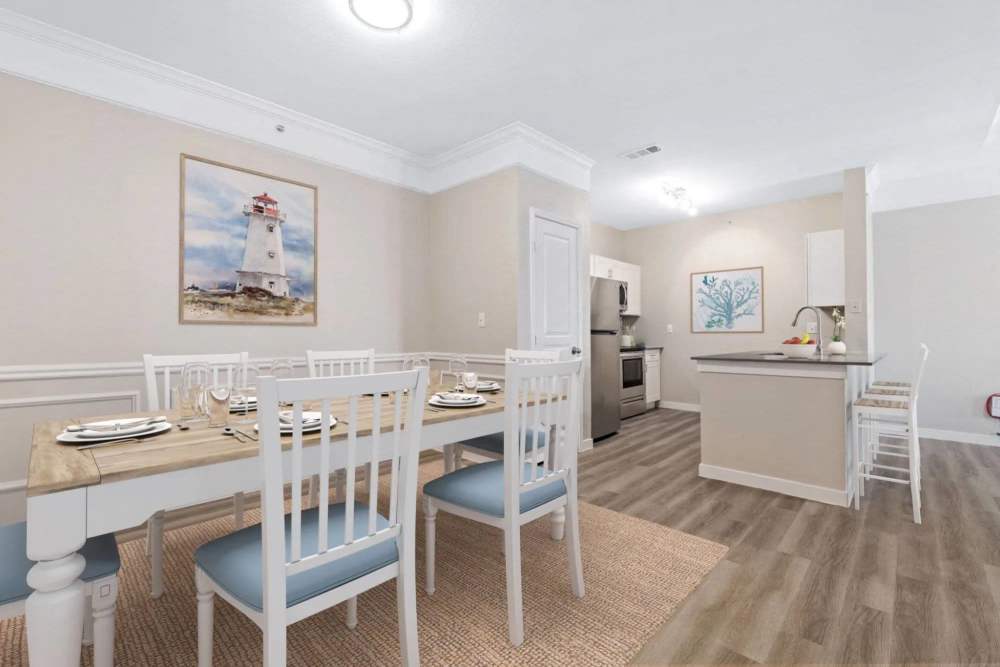 Bright dining area with wood-style flooring and a fully-equipped kitchen featuring stainless steel appliances and island seating at Reeves and Wells in Dallas, Texas