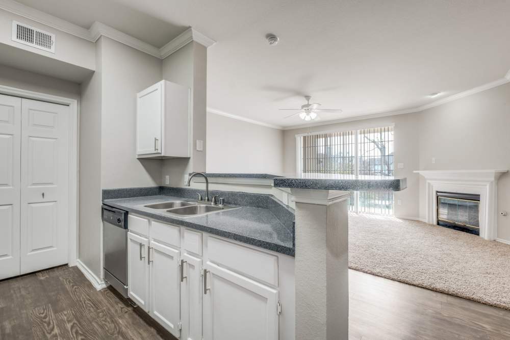 Open layout kitchen with granite countertops and stainless steel appliances, wood-style flooring, and cozy living area at Reeves and Wells in Dallas, Texas