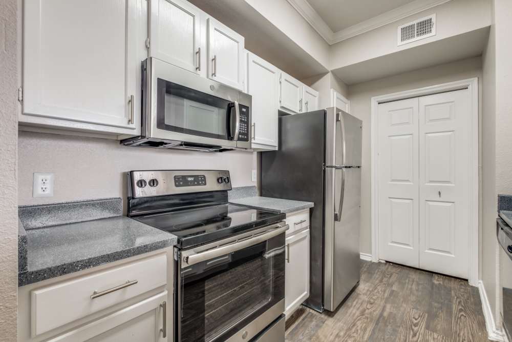 Modern kitchen with stainless steel appliances, granite countertops, and wood-style flooring at Reeves and Wells in Dallas, Texas