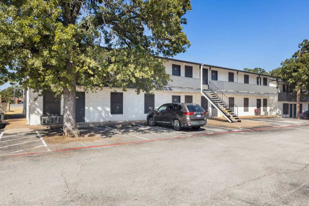 Exterior of two-story white apartment building with black doors and exterior stairs at Country Oaks in Weatherford, Texas