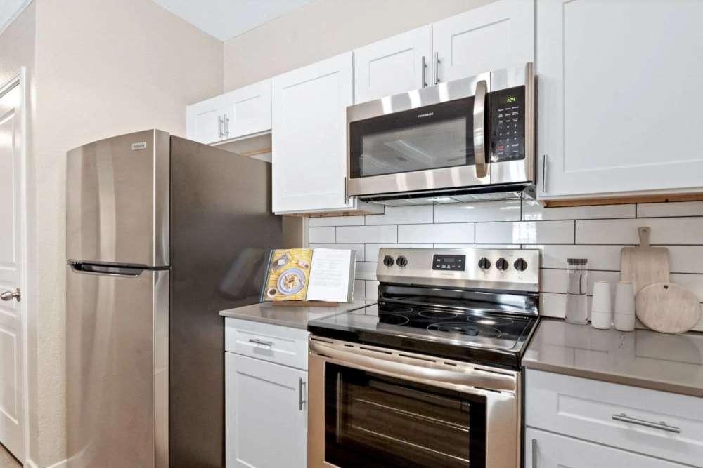 Modern kitchen with stainless steel appliances, granite countertops, and white cabinetry at Reeves and Wells in Dallas, Texas