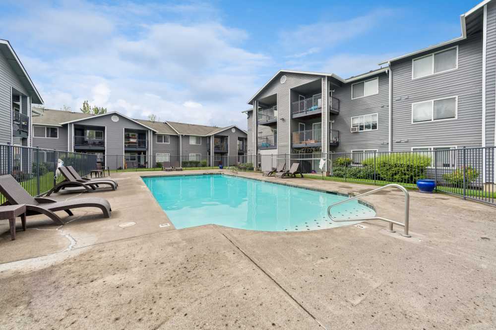 Swimming pool with lounge chairs and apartment buildings at Fieldstone in Fairview, Oregon.