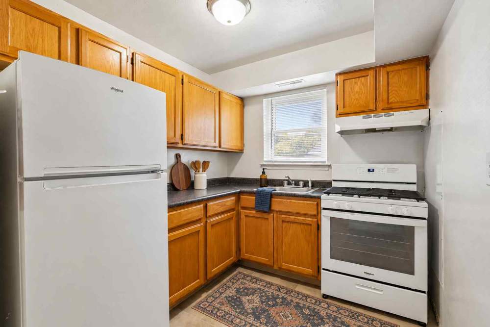 Modern kitchen with brown cabinets and white appliances at Post & Coach Apartment Homes in Freehold, New Jersey