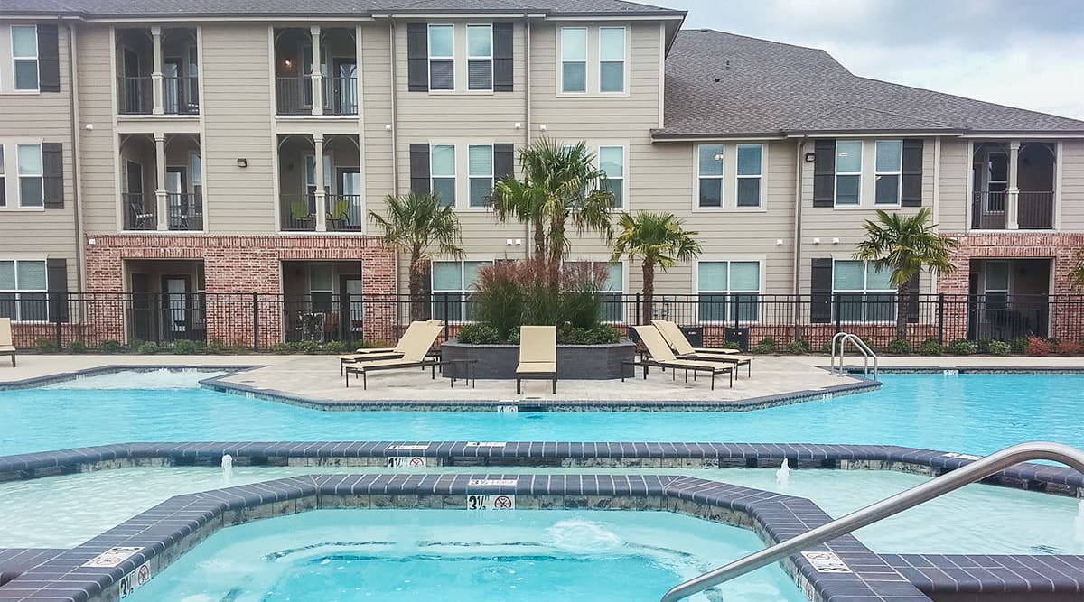 Resort-style pool with palm trees at Le Rivage Luxury Apartments in Bossier City, Louisiana