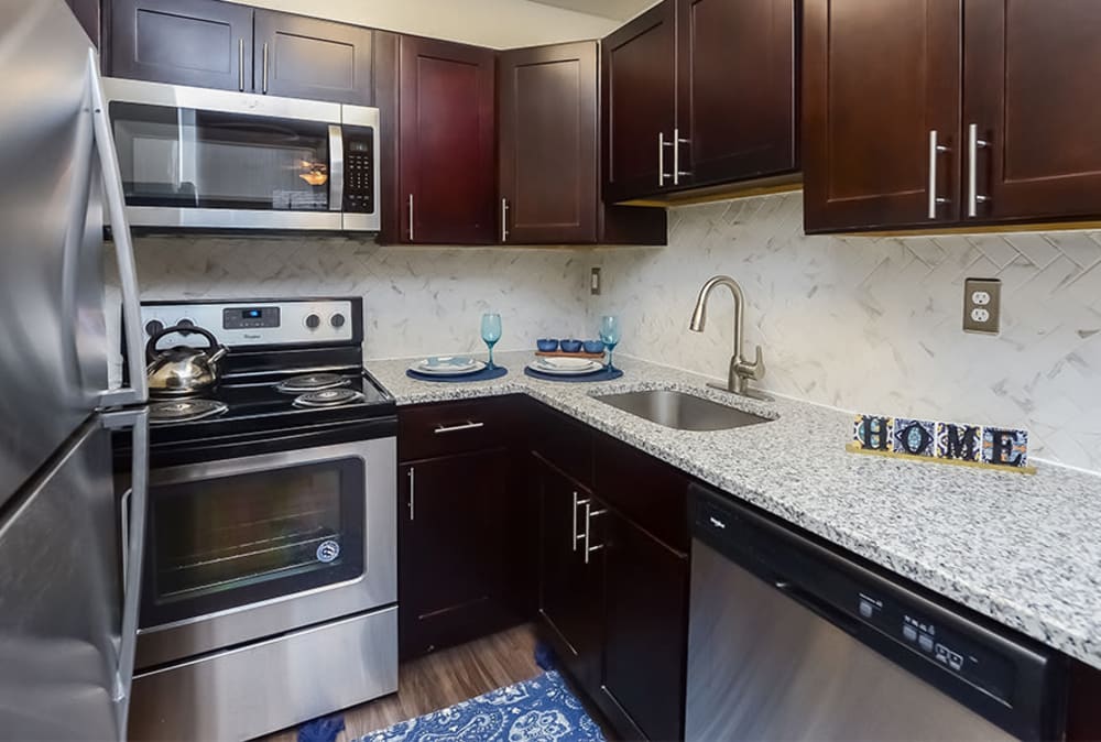 Kitchen with espresso cabinetry and stainless-steel appliances at Hyde Park Apartment Homes in Bellmawr, New Jersey