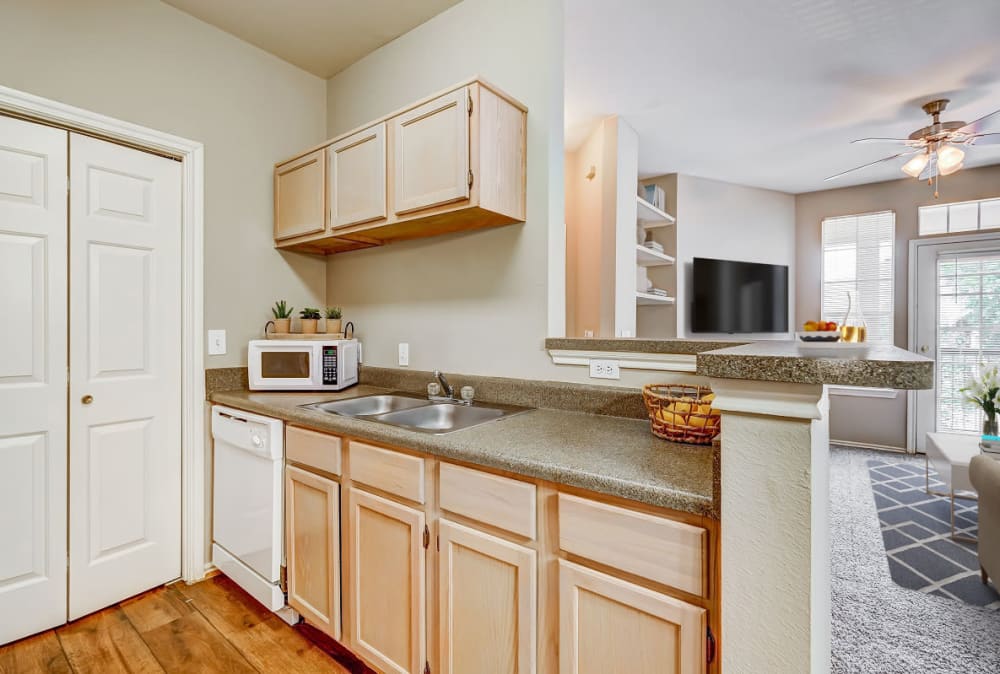 Kitchen cabinets with side view of living room at Champion Lake Apartment Homes in Shreveport, Louisiana
