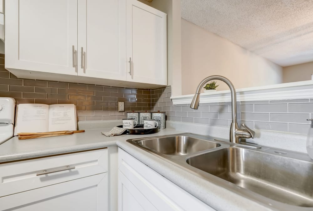Updated kitchen with white cabinets, tile backsplash, and white appliances Lakewood Apartment Homes in Salisbury, North Carolina