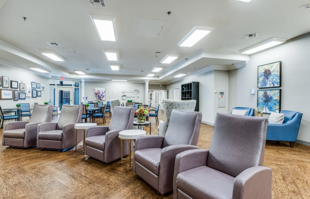 Great Room with comfortable chairs facing a flat-screen television at Iris Memory Care of Turtle Creek in Dallas, Texas. 