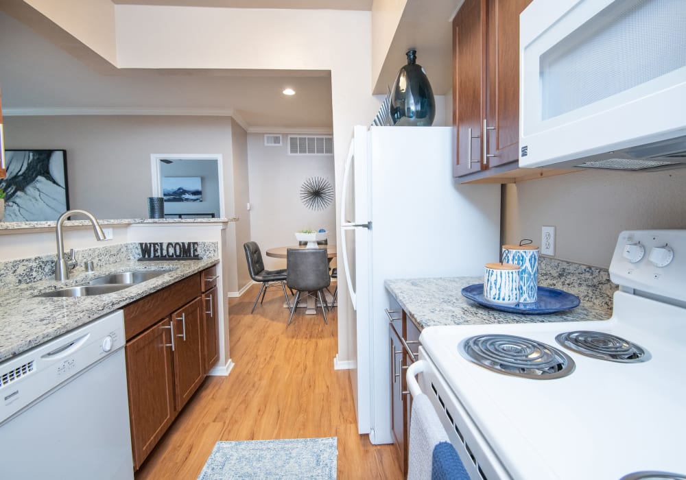 A bright kitchen with granite countertops and white appliances at Estates on Frankford in Dallas, Texas