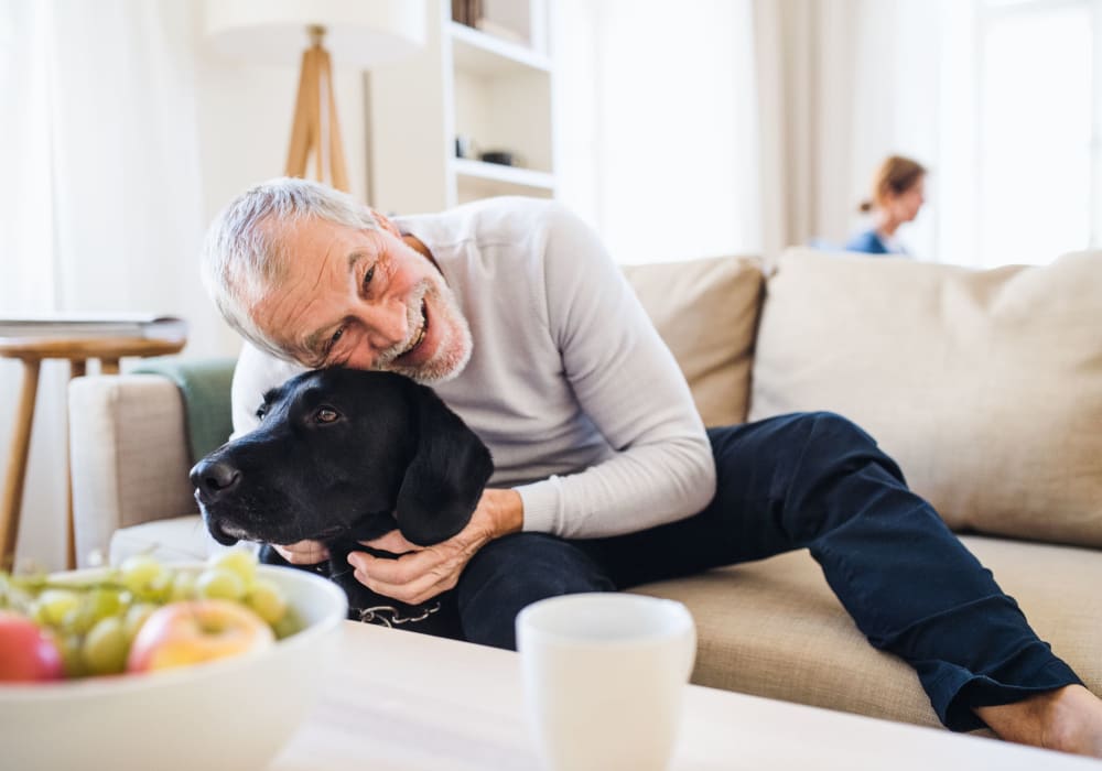 Man posing for a photo with his black labrador in his bright, inviting living room at Salony House Apartments in Reisterstown, Maryland