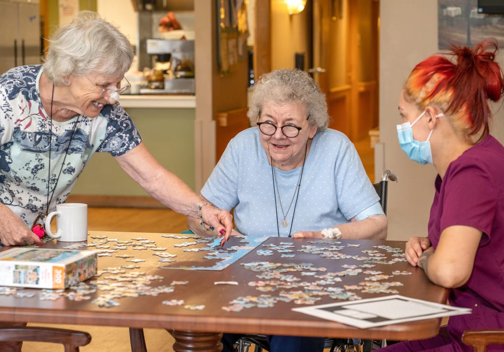Residents and a caregiver solving a jigsaw puzzle at Wellington Place at Rib Mountain in Wausau, Wisconsin