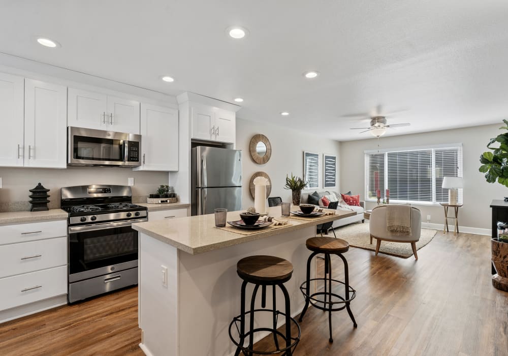 Kitchen with white Shaker-style cabinetry, stainless-steel appliances, and a breakfast bar at Pinebrook Apartments in Fremont, California