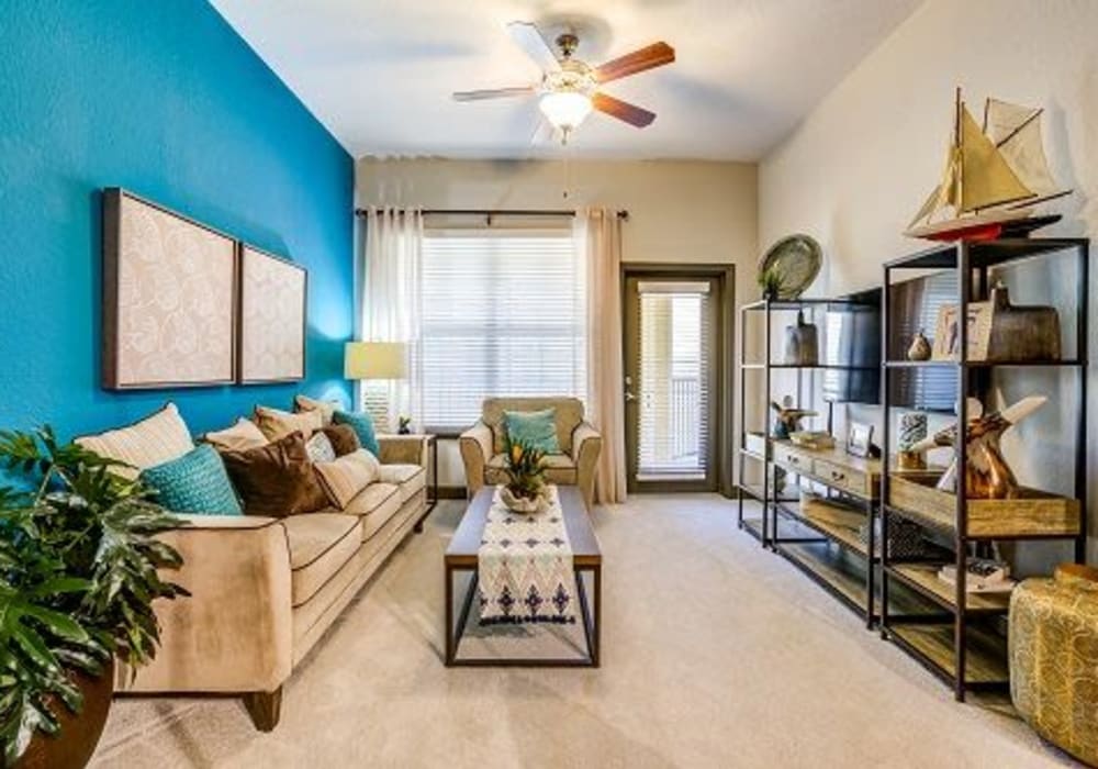 Cozy carpeted living room with ceiling fan at Addison at Tampa Oaks in Temple Terrace, Florida