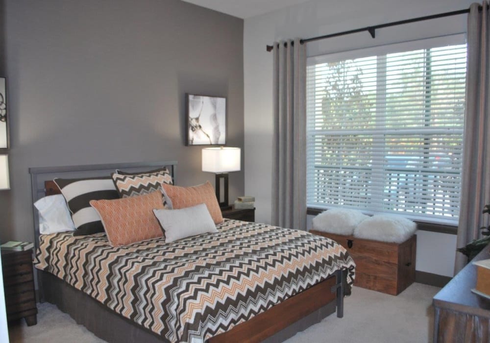 Full bed with multiple throw pillows and large window at Addison at Tampa Oaks in Temple Terrace, Florida