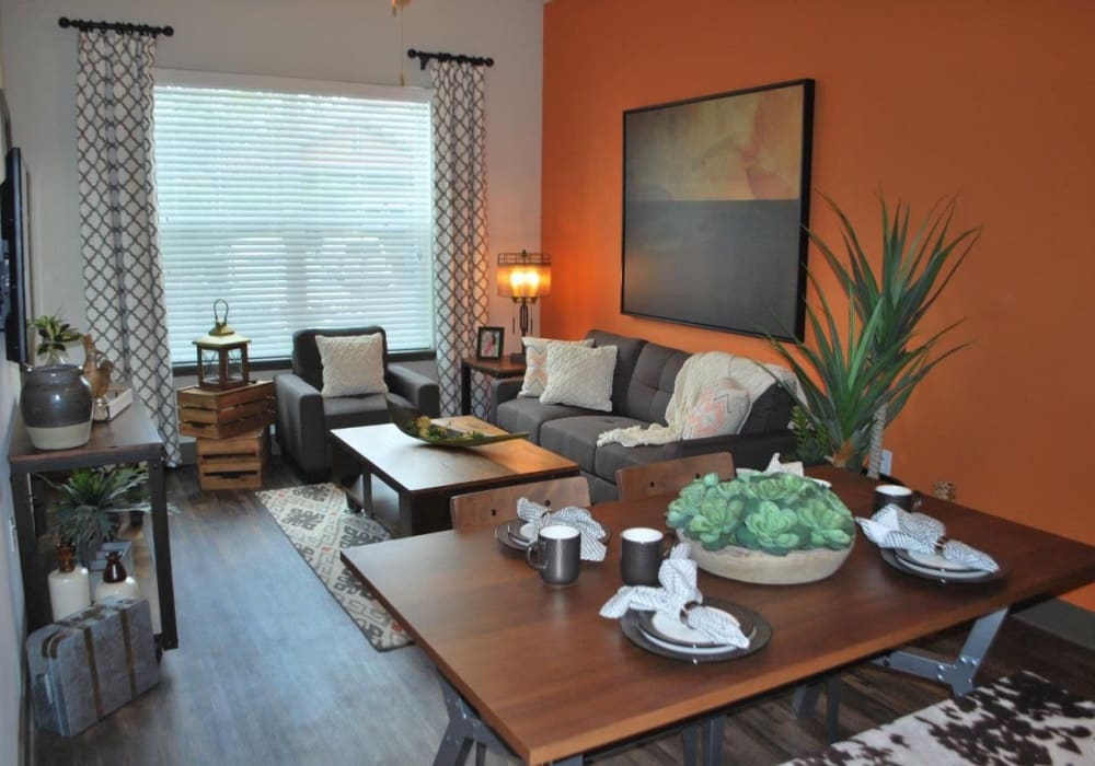 Furnished living room with leather sofa and orange painted wall at Addison at Tampa Oaks in Temple Terrace, Florida