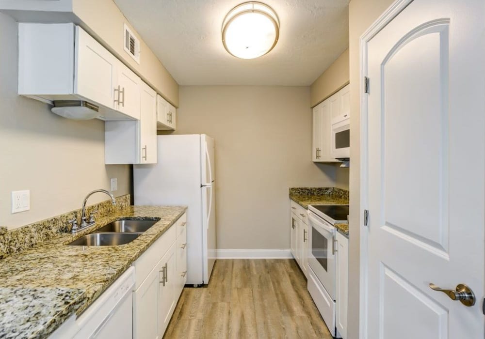 Apartment kitchen with granite counters and pantry at Garden Grove in Sarasota, Florida