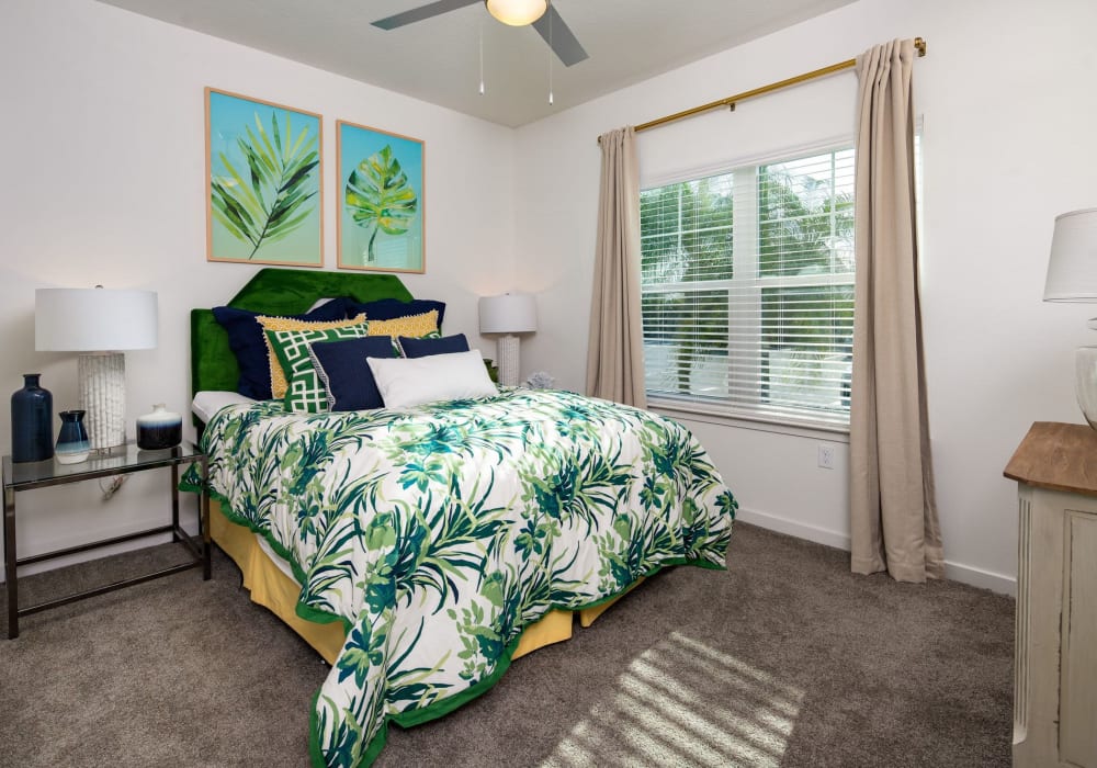 Carpeted apartment bedroom with ceiling fan and large sunny window at The Iris at Northpointe in Lutz, Florida