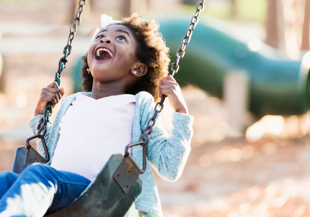 Happy girl swinging on swing in summer on a playground at Casablanca Apartments in Palmdale, California