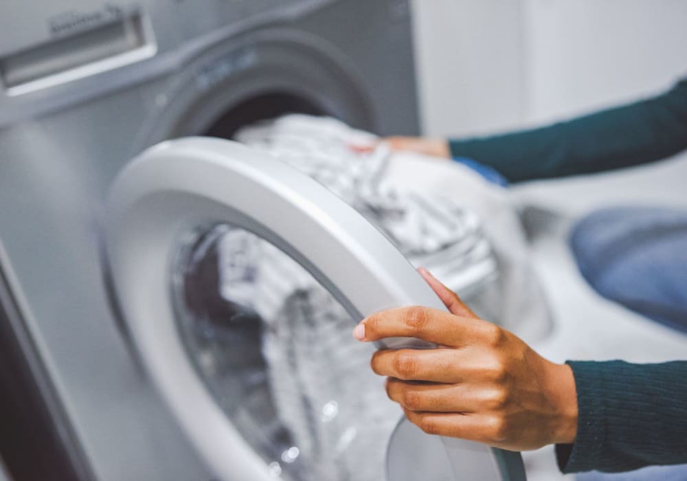 Close-Up of woman putting laundry In washing machine at Casablanca Apartments in Palmdale, California
