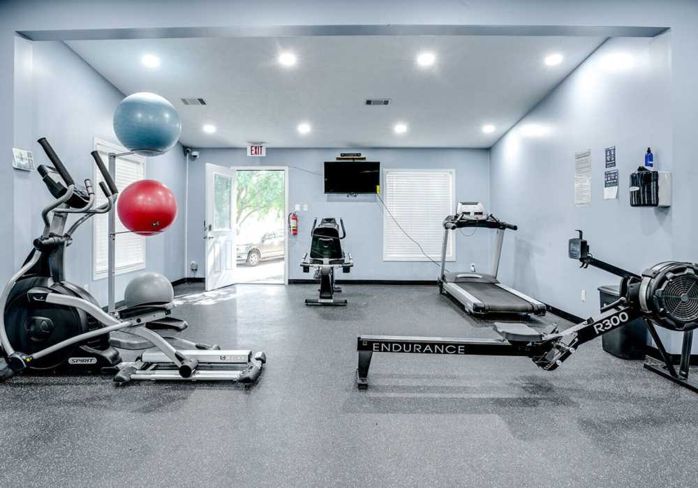 Fitness center with television at Waterstone Place Apartments in Stafford, Texas