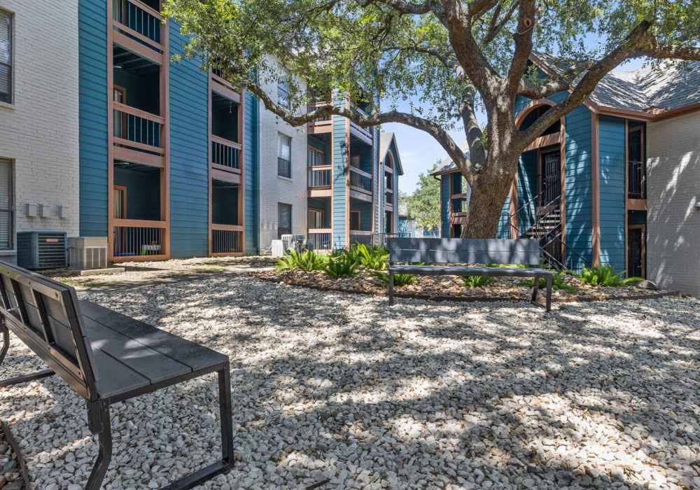 Community seating area with a bench surrounded by trees at Hill At Woodway in San Antonio, Texas