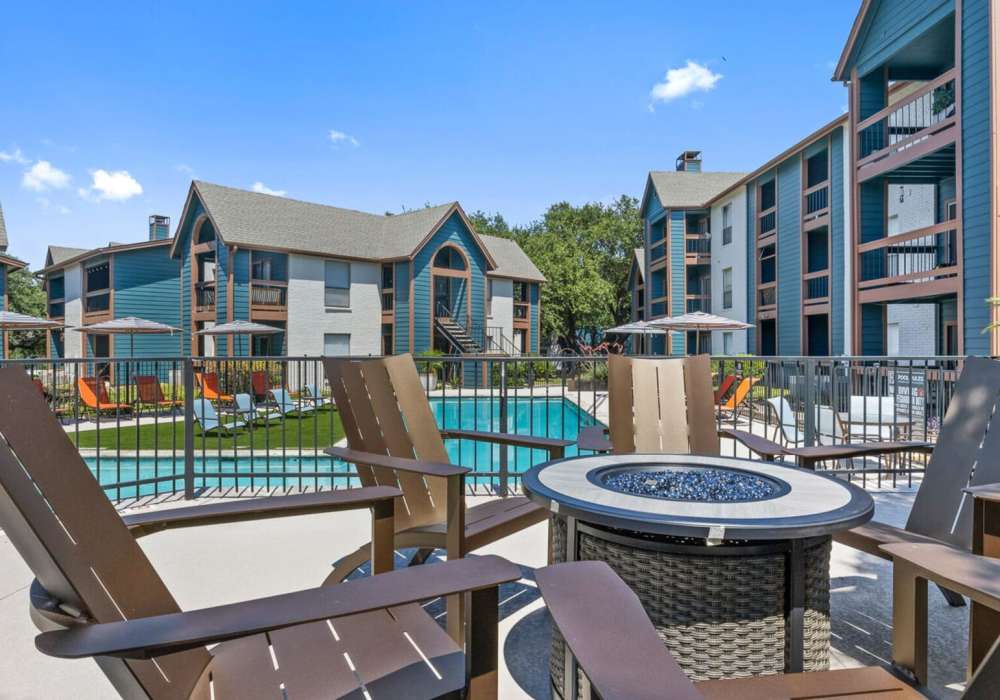 Seating area alongside pool with chairs and table at Hill At Woodway in San Antonio, Texas