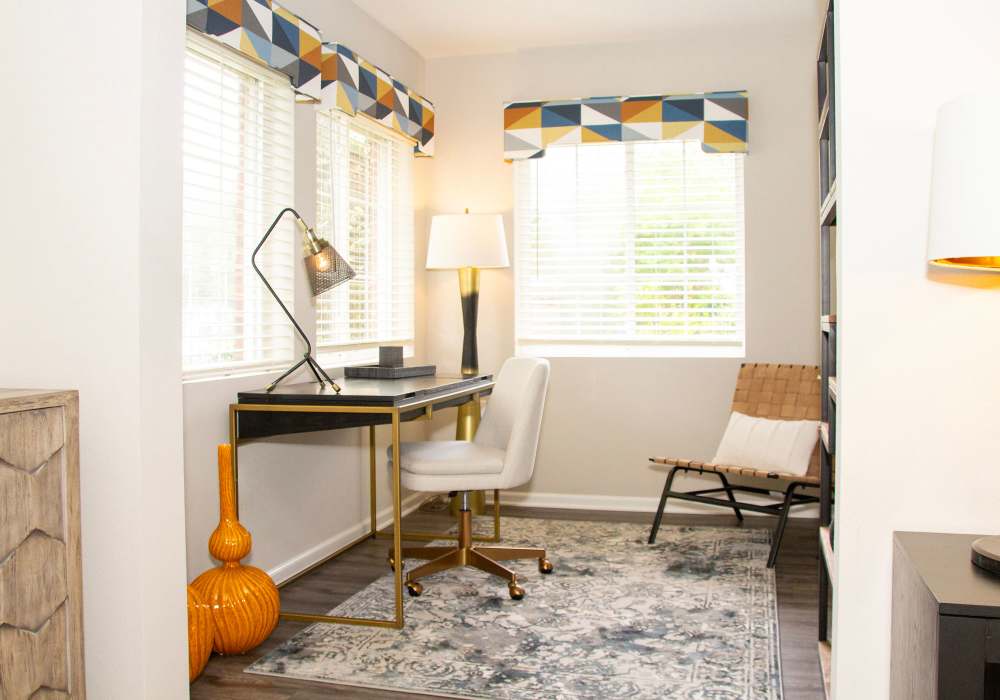 Open layout living room with hard-wood style flooring, a couch, coffee table, and chairs at Battleground North in Greensboro, North Carolina