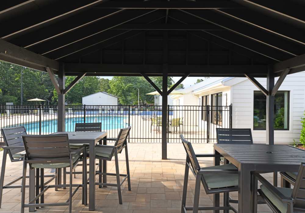 A covered patio area with tables and chairs beside the swimming pool at Ascent Apartment Homes in Asheville, North Carolina